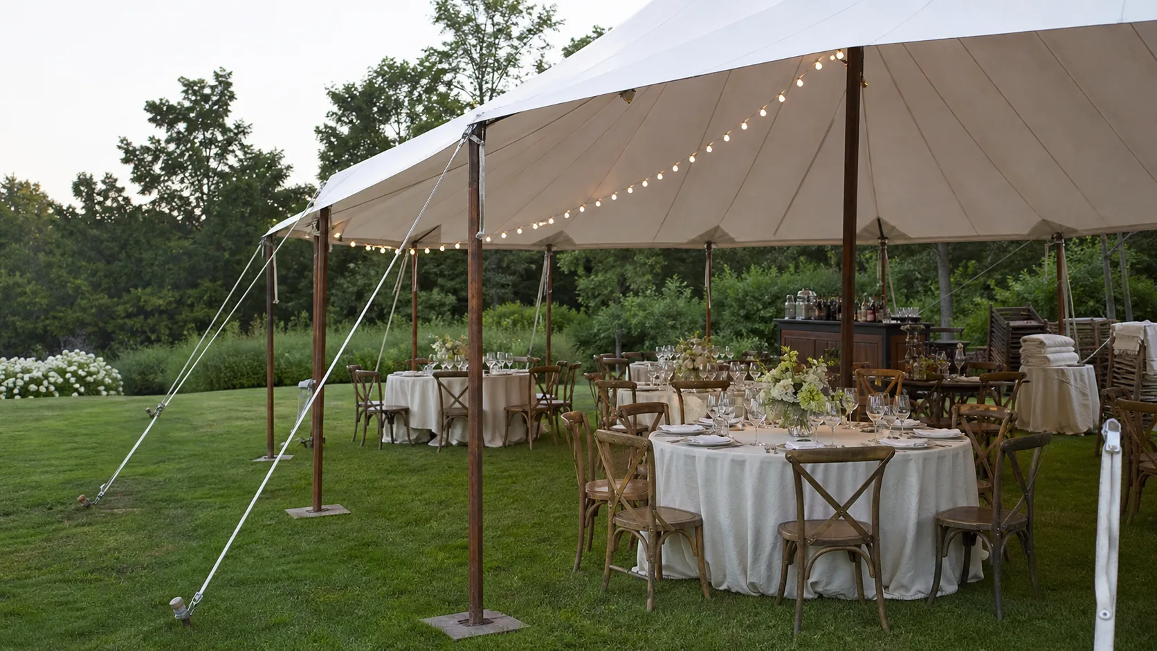 A professionally prepared outdoor rental reception under a sailcloth tent